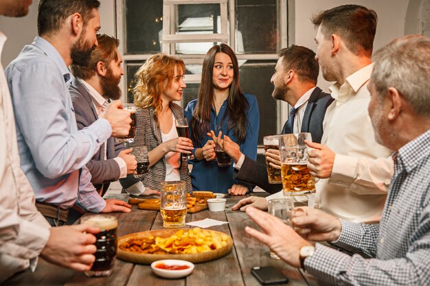 Grupo de amigos disfrutando de bebidas por la noche con cerveza