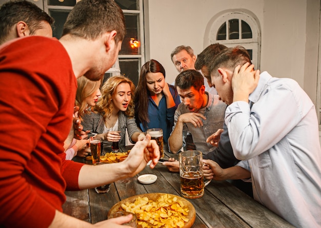 Grupo de amigos disfrutando de bebidas por la noche con cerveza