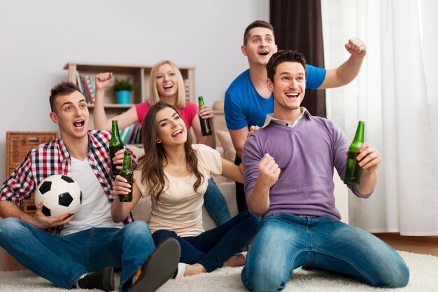 Grupo de amigos disfrutando del fútbol en la televisión