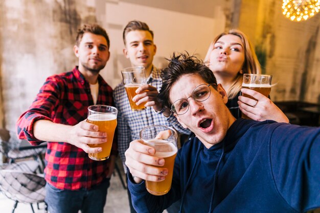 Grupo de amigos disfrutando de la selfie disfrutando de la cerveza en pub.