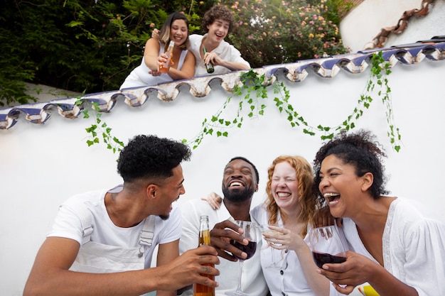 Grupo de amigos divirtiéndose durante una fiesta blanca con bebidas