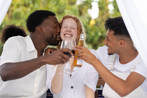 Grupo de amigos divirtiéndose durante una fiesta blanca con bebidas