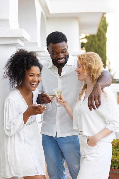 Grupo de amigos divirtiéndose durante una fiesta blanca con bebidas