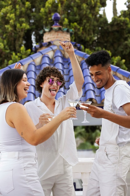 Grupo de amigos divirtiéndose durante una fiesta blanca con bebidas