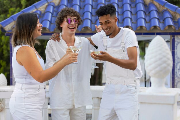 Grupo de amigos divirtiéndose durante una fiesta blanca con bebidas