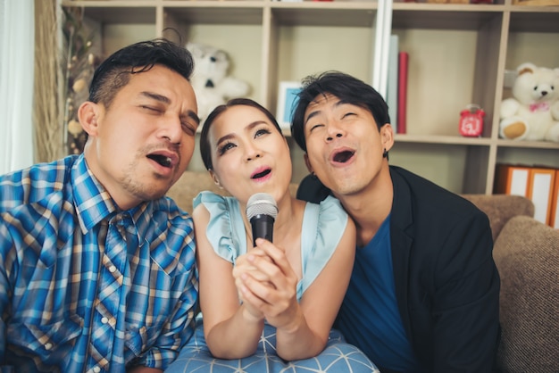 Grupo de amigos divirtiéndose en la sala de estar cantando una canción juntos