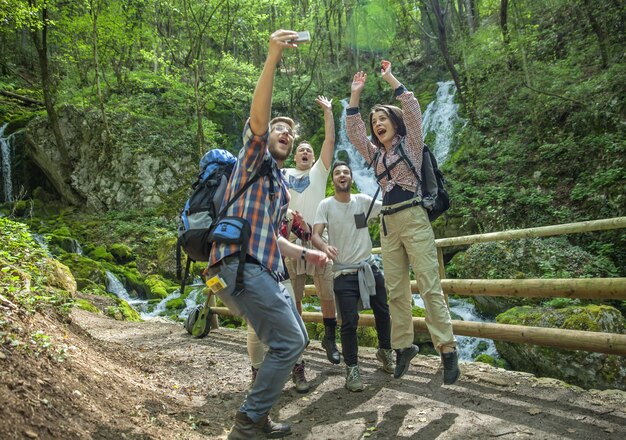 Grupo de amigos divirtiéndose y tomando selfies en la naturaleza.