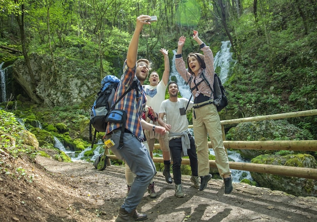 Grupo de amigos divirtiéndose y tomando selfies en la naturaleza.