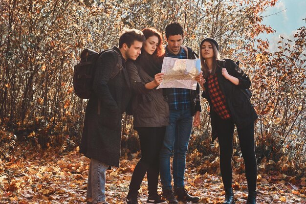 Un grupo de amigos está buscando en el mapa dónde están en el parque de hojas doradas.