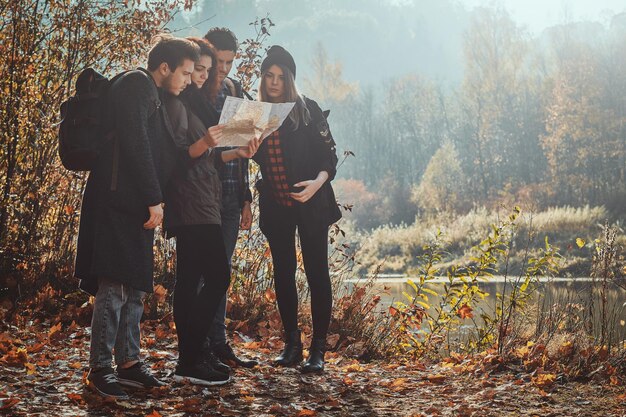 Un grupo de amigos está buscando en el mapa dónde están en el parque de hojas doradas.