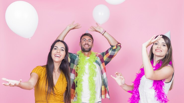 Foto gratuito grupo de amigos felices bailando en el contexto rosado