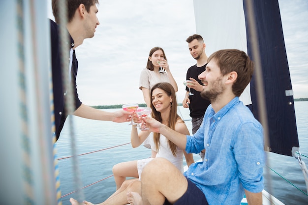 Grupo de amigos felices bebiendo cócteles de vodka en un bote