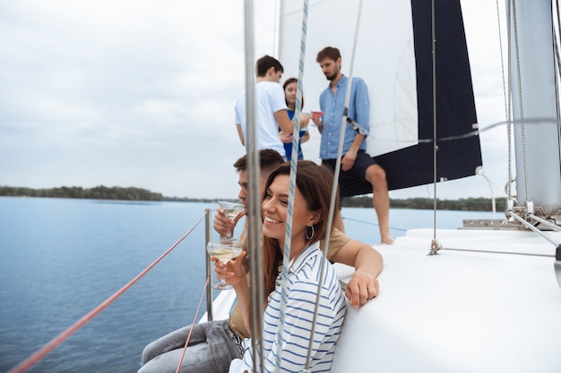 Grupo de amigos felices bebiendo cócteles de vodka en fiesta en barco al aire libre, verano