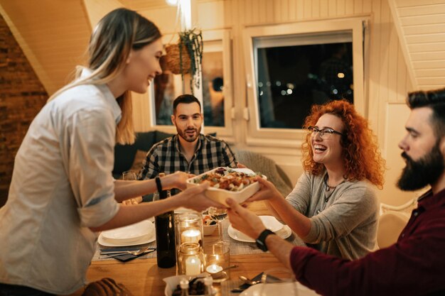 Grupo de amigos felices divirtiéndose mientras cenan juntos en casa