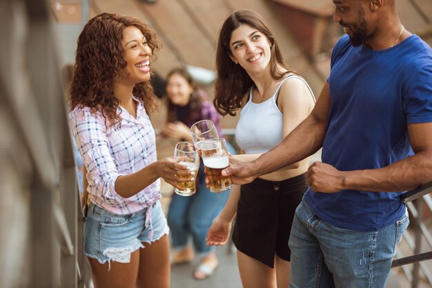 Grupo de amigos felices con fiesta de cerveza en día de verano. Descansar juntos al aire libre, celebrar y relajarse, reír. Estilo de vida de verano, concepto de amistad.