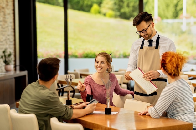 Grupo de amigos felices hablando mientras hacen un pedido en un café