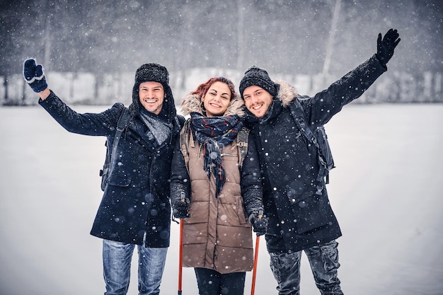 Foto gratuita un grupo de amigos felices se paran uno al lado del otro y miran la cámara en medio de un bosque nevado