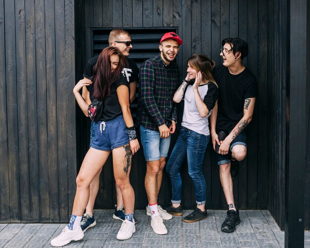 Grupo de amigos felices que se burlan delante de la pared de madera