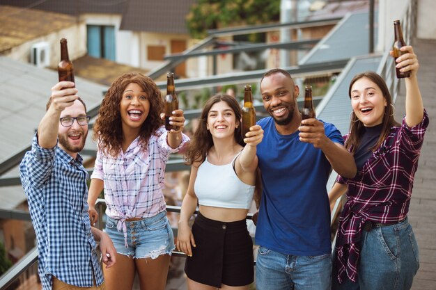 Grupo de amigos felices que tienen fiesta de la cerveza en un día soleado.