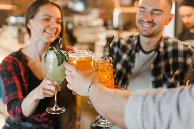 Grupo de amigos felices tostado bebidas mientras de fiesta en pub