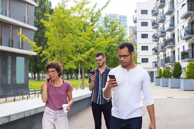 Grupo de amigos con gadgets caminando afuera