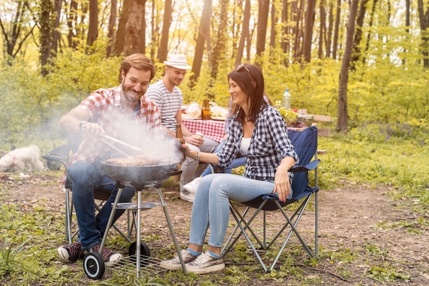 Grupo de amigos haciendo barbacoa en el bosque en verano