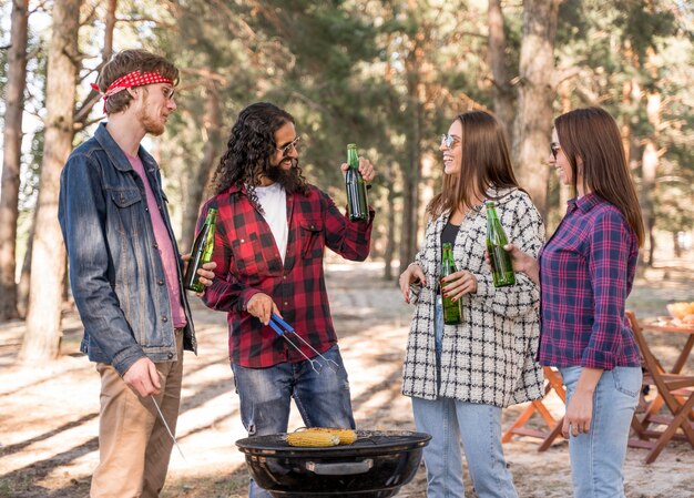 Grupo de amigos haciendo una barbacoa con cervezas