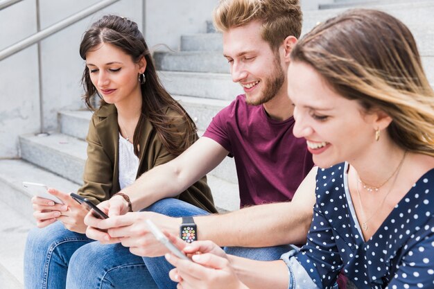 Grupo de amigos jóvenes felices que usan el teléfono móvil