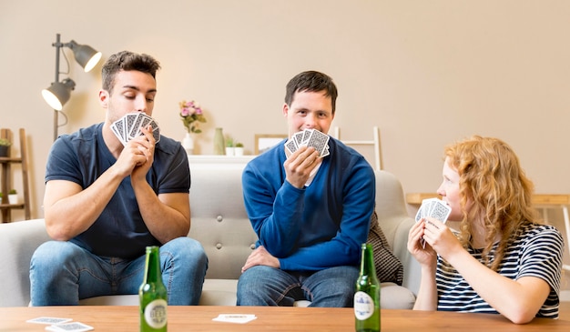 Foto gratuita grupo de amigos jugando a las cartas en casa y tomando cerveza