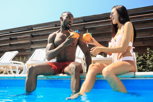 Grupo de amigos jugando y relajándose en una piscina durante las vacaciones de verano