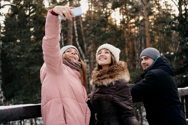 Grupo de amigos juntos tomando selfie al aire libre en invierno