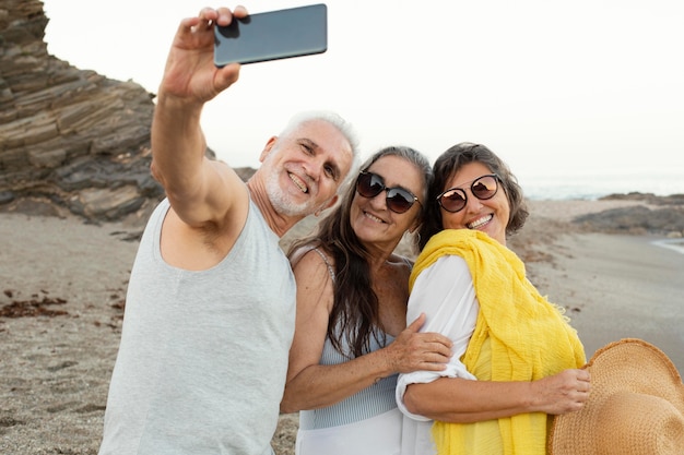 Grupo de amigos mayores tomando selfie con smartphone en la playa