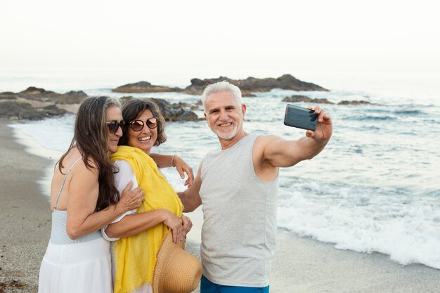 Grupo de amigos mayores tomando selfie con smartphone en la playa