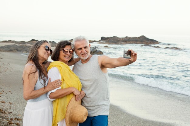 Grupo de amigos mayores tomando selfie con smartphone en la playa