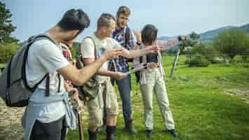 Foto gratuita grupo de amigos con mochilas revisando el mapa y apuntando a algún lugar