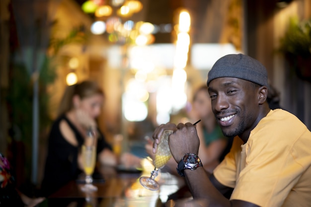 Grupo de amigos multiétnicos bebiendo cócteles y divirtiéndose en un bar