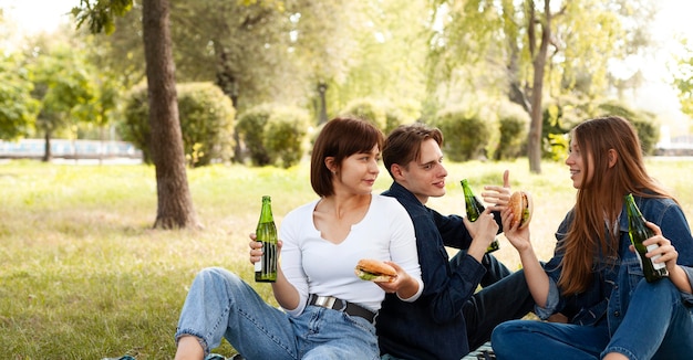 Grupo de amigos en el parque con hamburguesas y cerveza.