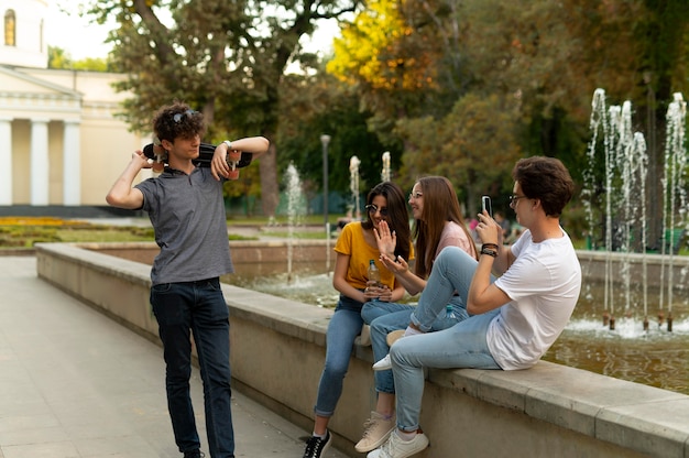 Grupo de amigos, pasar tiempo juntos al aire libre junto a la fuente