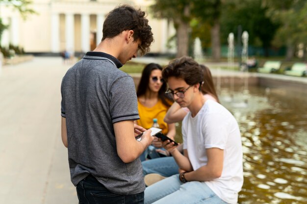 Grupo de amigos, pasar tiempo juntos al aire libre junto a la fuente