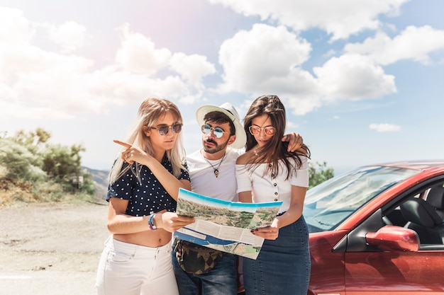 Grupo de amigos de pie cerca del coche mirando el mapa