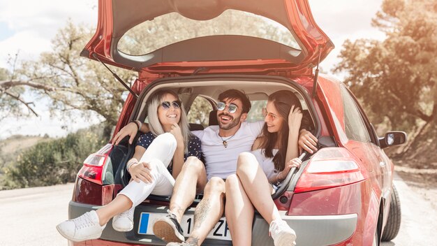 Grupo de amigos que disfrutan en el baúl del auto en la carretera