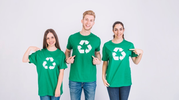 Grupo de amigos que muestran el icono de reciclaje en su camiseta verde