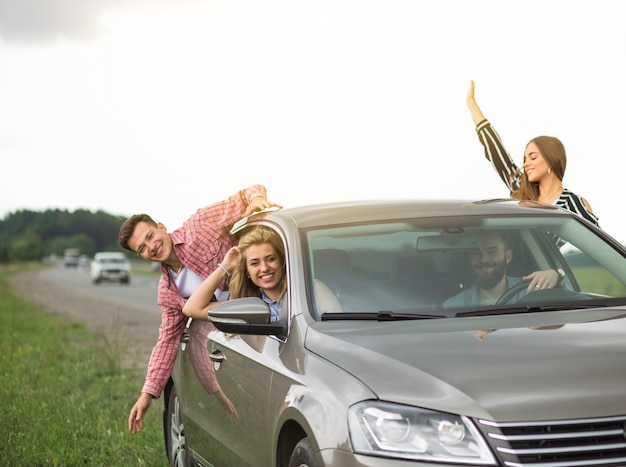 Grupo de amigos que viajan en el coche pasando por la ventana abierta