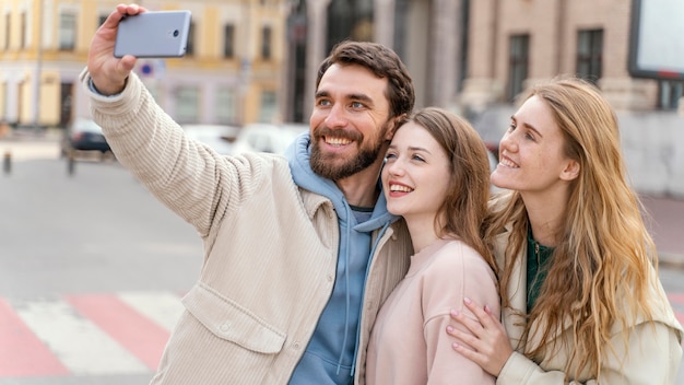 Grupo de amigos sonrientes al aire libre en la ciudad tomando selfie