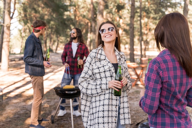 Grupo de amigos sonrientes con cervezas sobre barbacoa