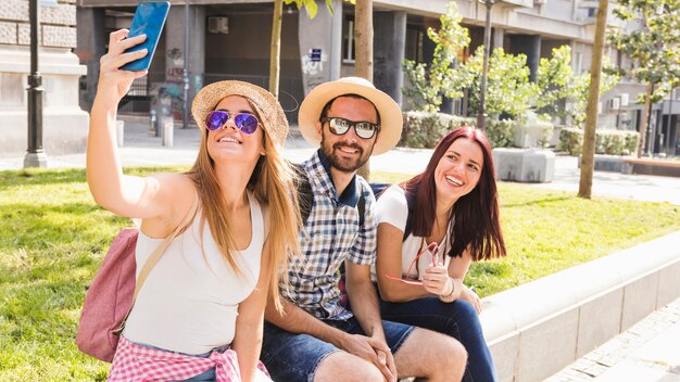 Grupo de amigos sonrientes tomando selfie en celular