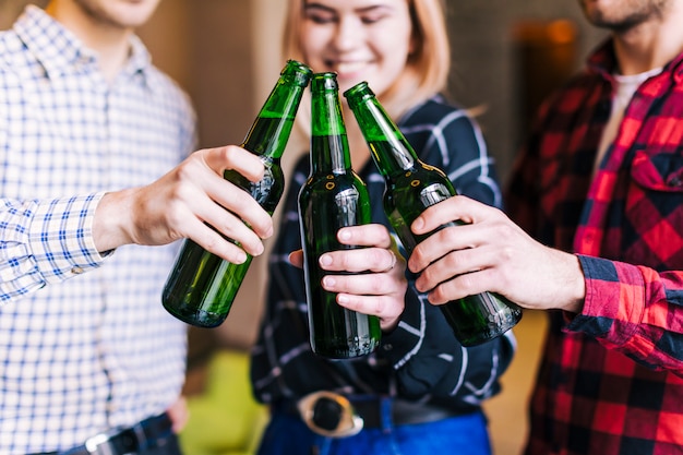 Foto gratuita grupo de amigos tintineando botellas de cerveza en el pub