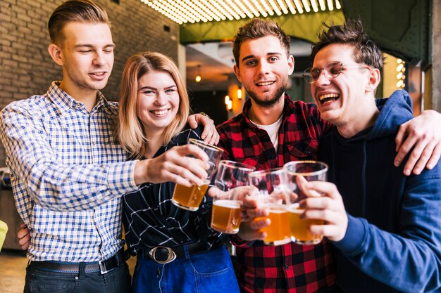 Grupo de amigos tintineando los vasos de cerveza en pub