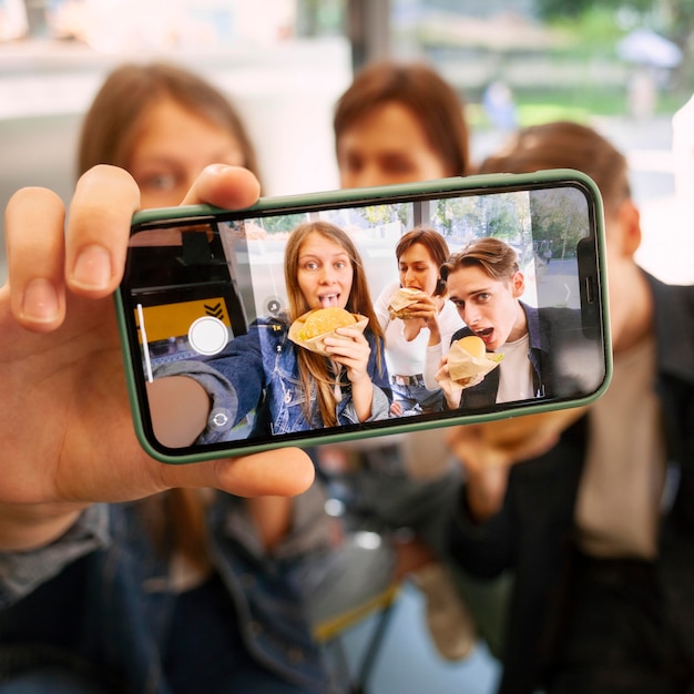 Grupo de amigos tomando selfie juntos mientras comen comida rápida