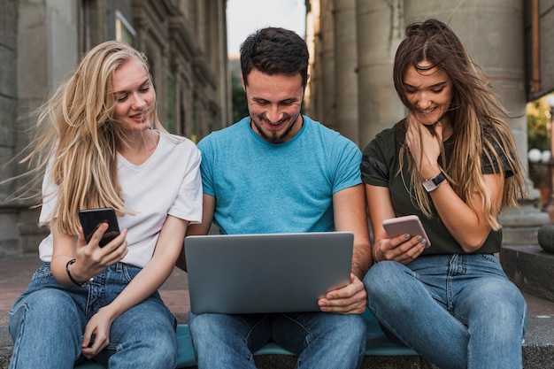 Grupo de amigos trabajando en teléfonos y computadoras portátiles